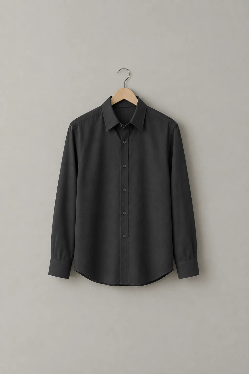 A single crisp, pressed dark collared shirt hanging on a wooden hanger against a plain wall.